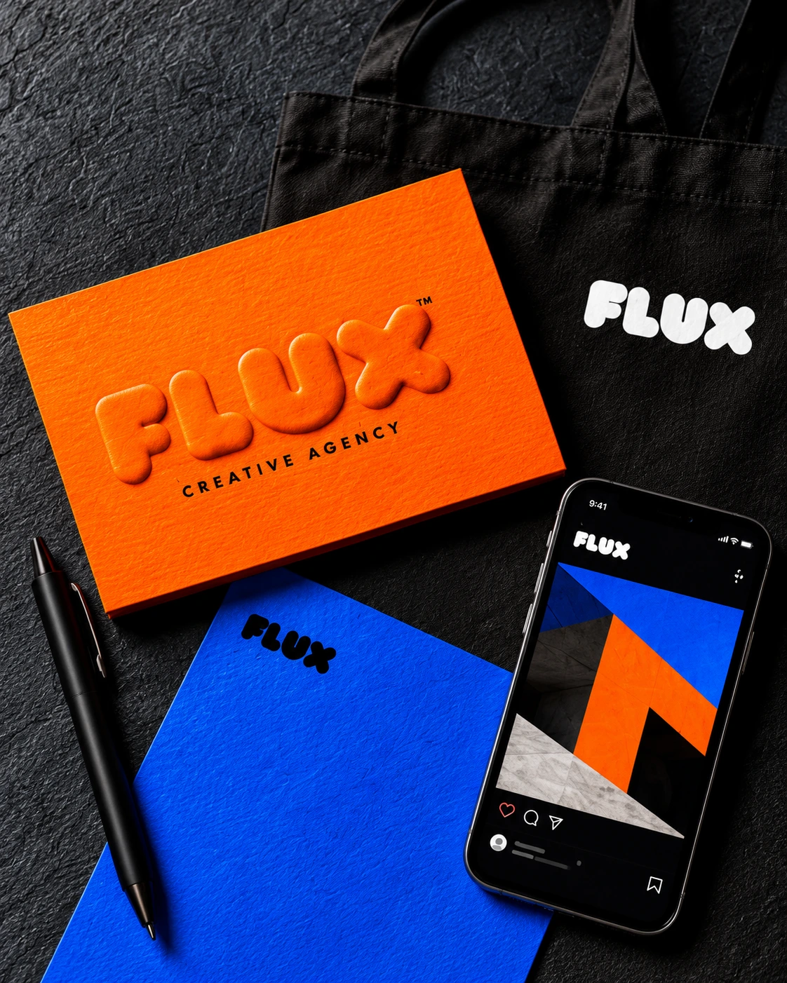 Flux embossed orange stationery, blue notebook, black tote and mobile brand artwork